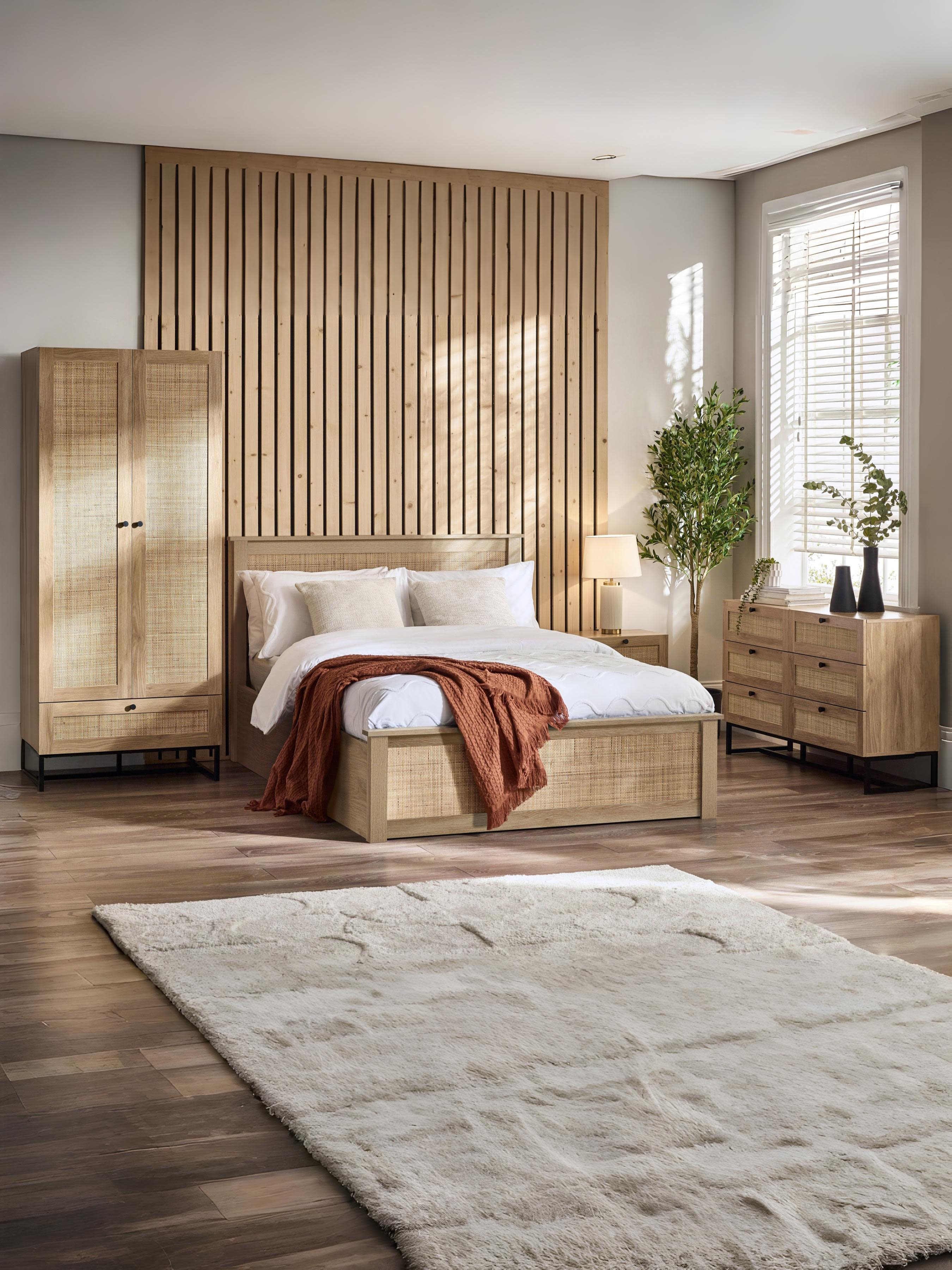 Julian Bowen Padstow oak effect rattan ottoman bed in a large bedroom, wide view