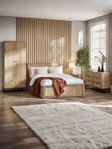 Julian Bowen Padstow oak effect rattan ottoman bed in a large bedroom, wide view