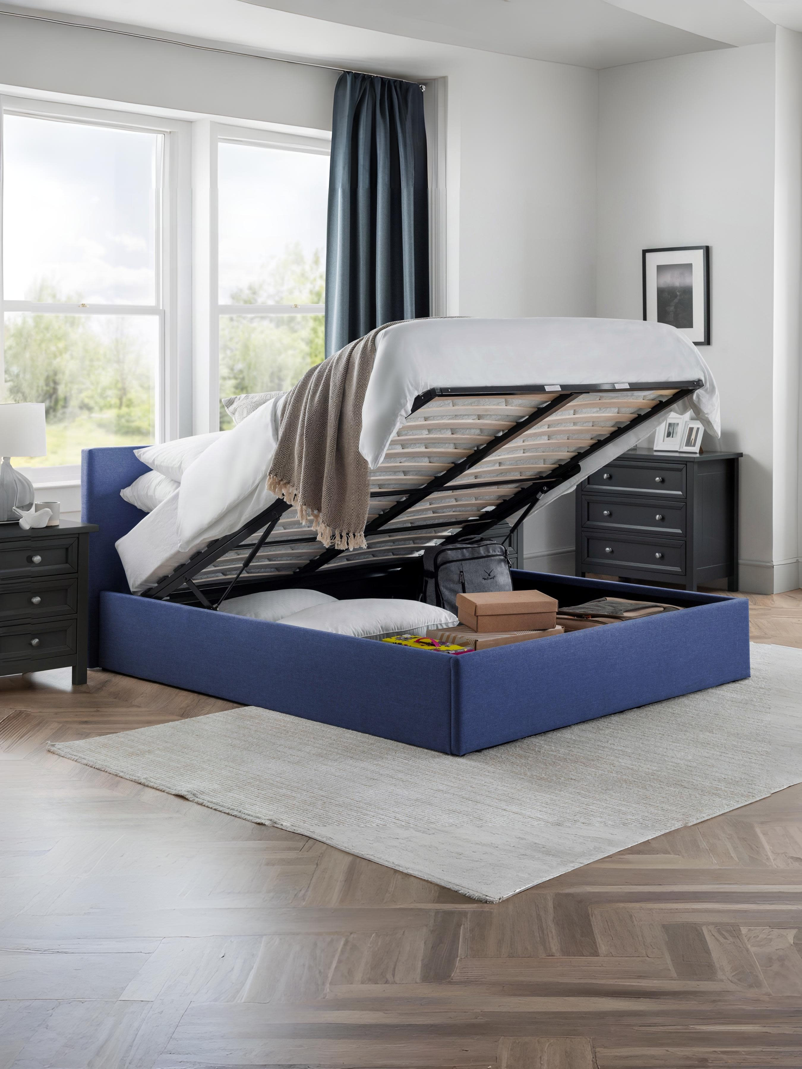 Julian Bowen Rialto blue ottoman bed with the base lifted to show the storage, in a bedroom