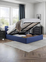 Julian Bowen Rialto blue ottoman bed with the base lifted to show the storage, in a bedroom