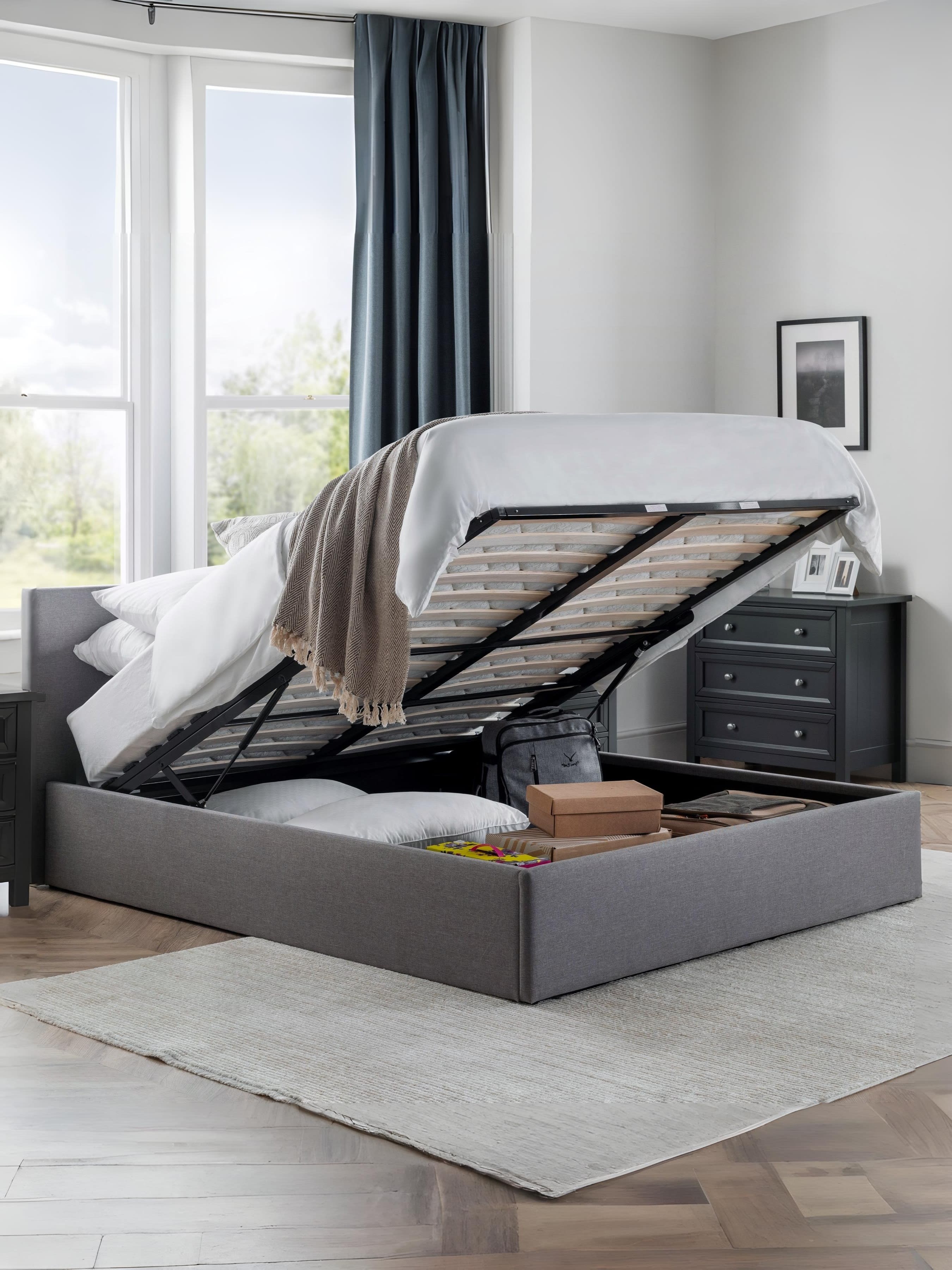 Julian Bowen Rialto grey ottoman bed with the base lifted to show the storage, in a bedroom