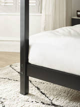 Roxanne canopy bed: black post and side rail in a bedroom, close up