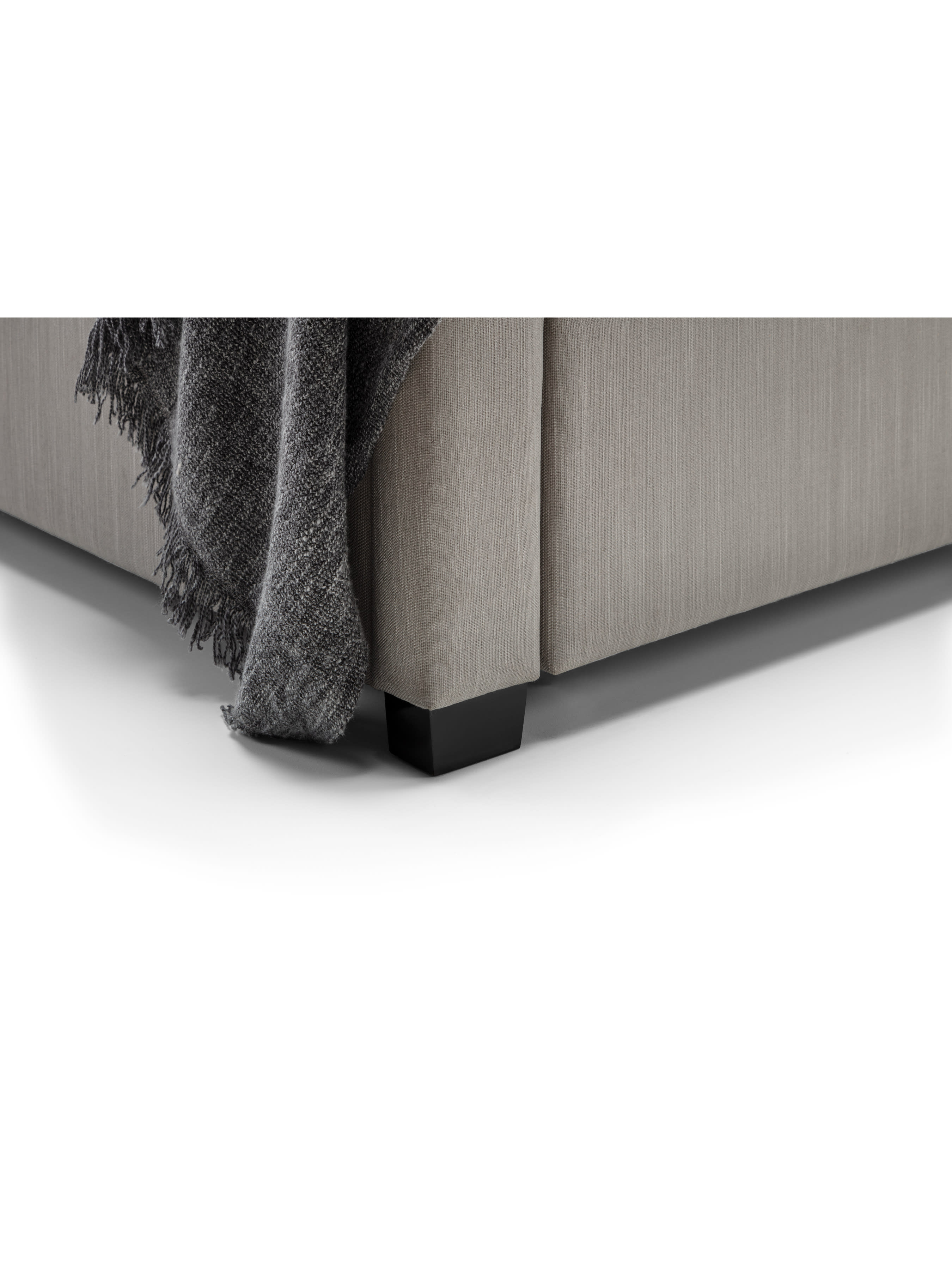 Wilton bed: corner of the light grey base and dark foot, close up