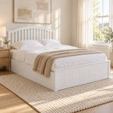 Barnet white wooden ottoman bed with a curved slatted headboard, in a bright bedroom (AI-generated illustration of this frame; bedding for illustration, mattress not included)