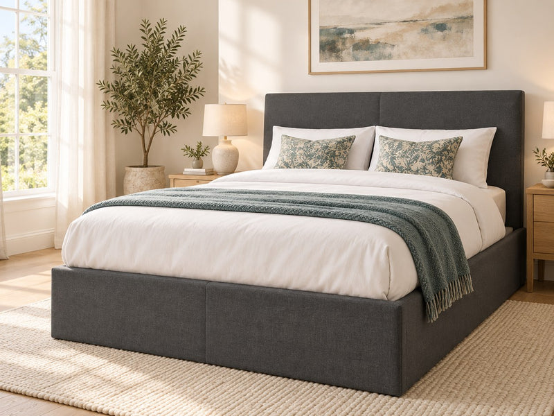 Sydenham grey fabric ottoman bed with a 115 cm headboard, seen from the side in a bright bedroom