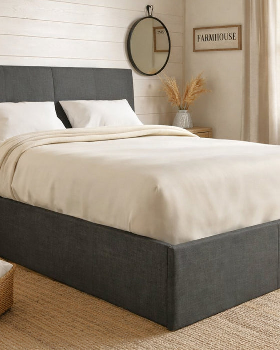 Sydenham grey fabric ottoman bed in a bedroom, made up with cream bedding